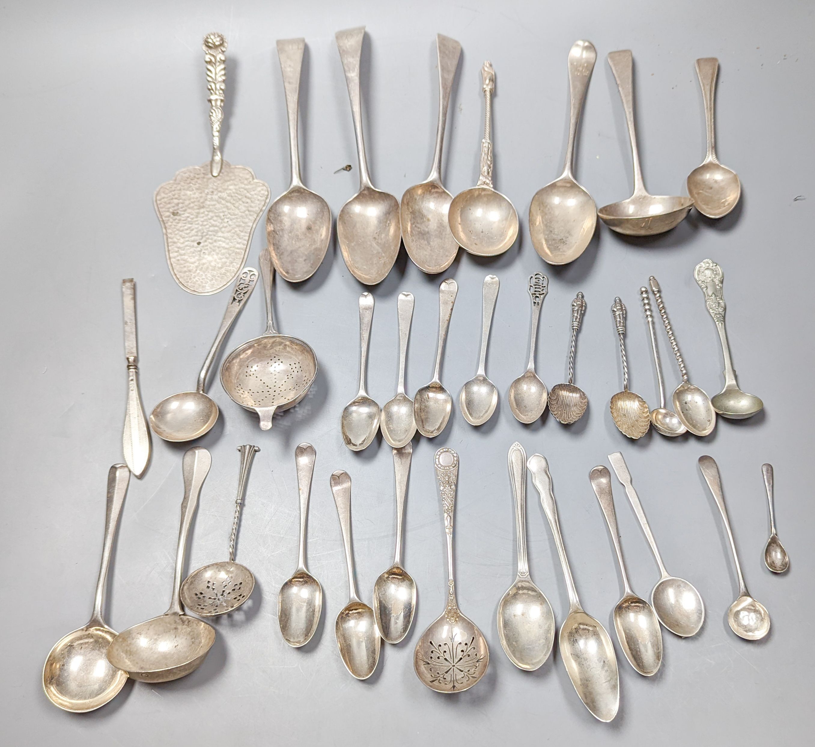 A mixed quantity of 18th, 19th and 20th century silver flatware, including tablespoons, teaspoons, sauce ladles, a 900 standard cake slice, two plated spoons and a nail implement